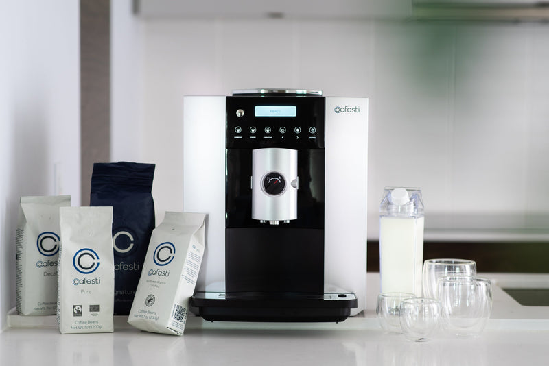 Cafesti machine and coffee subscription product shot showing Barista Touch automatic coffee machine with milk accessories, complimentary glass cups and cafesti coffee bean bags