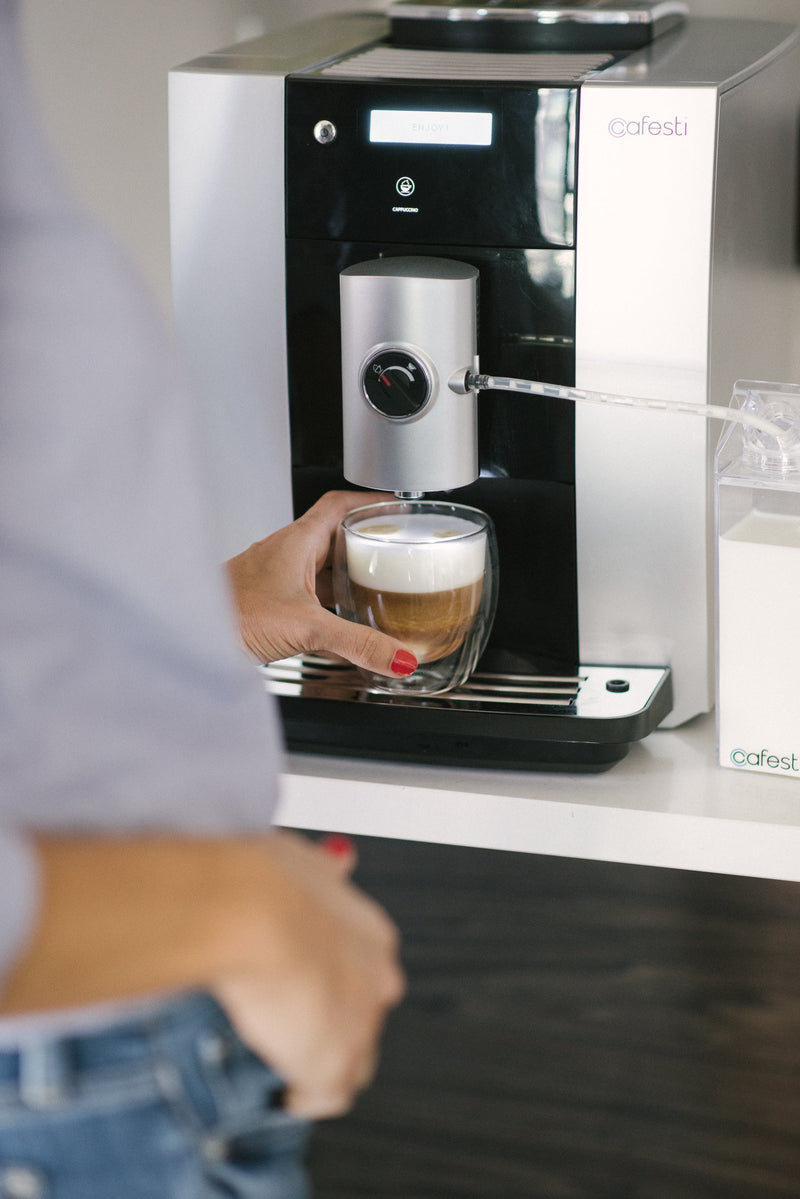 A hand grabbing a perfect cappuccino made by cafesti automatic coffee machine   