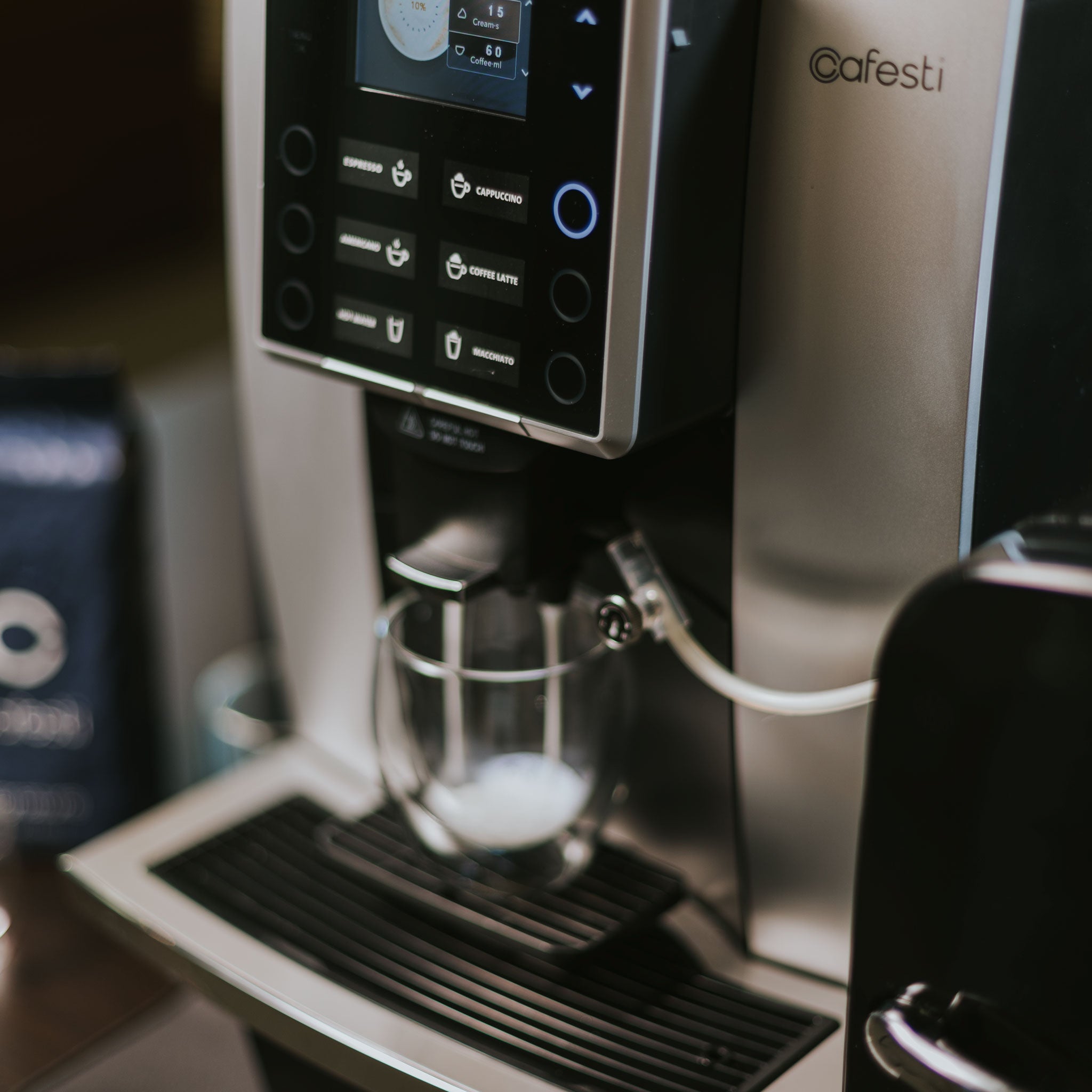 Cafesti Grande automatic coffee machine making a milk-based coffee drink- image showing the frothed milk dispensed into a glass cup